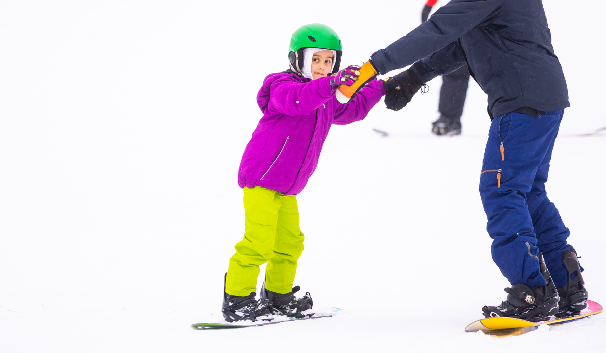 young girl learning to snowboard on a ski holiday