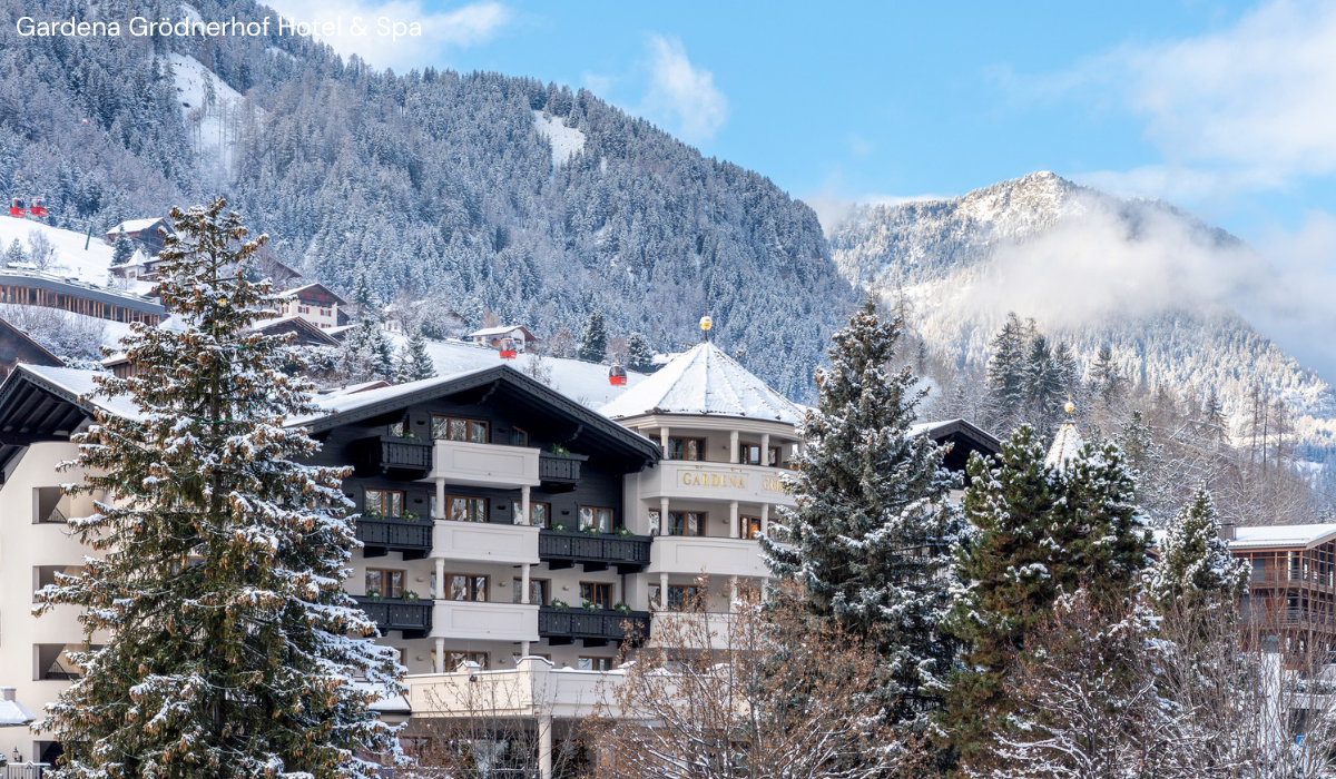 alpine trees covered in snow with the Gardena Hotel peaking trough.