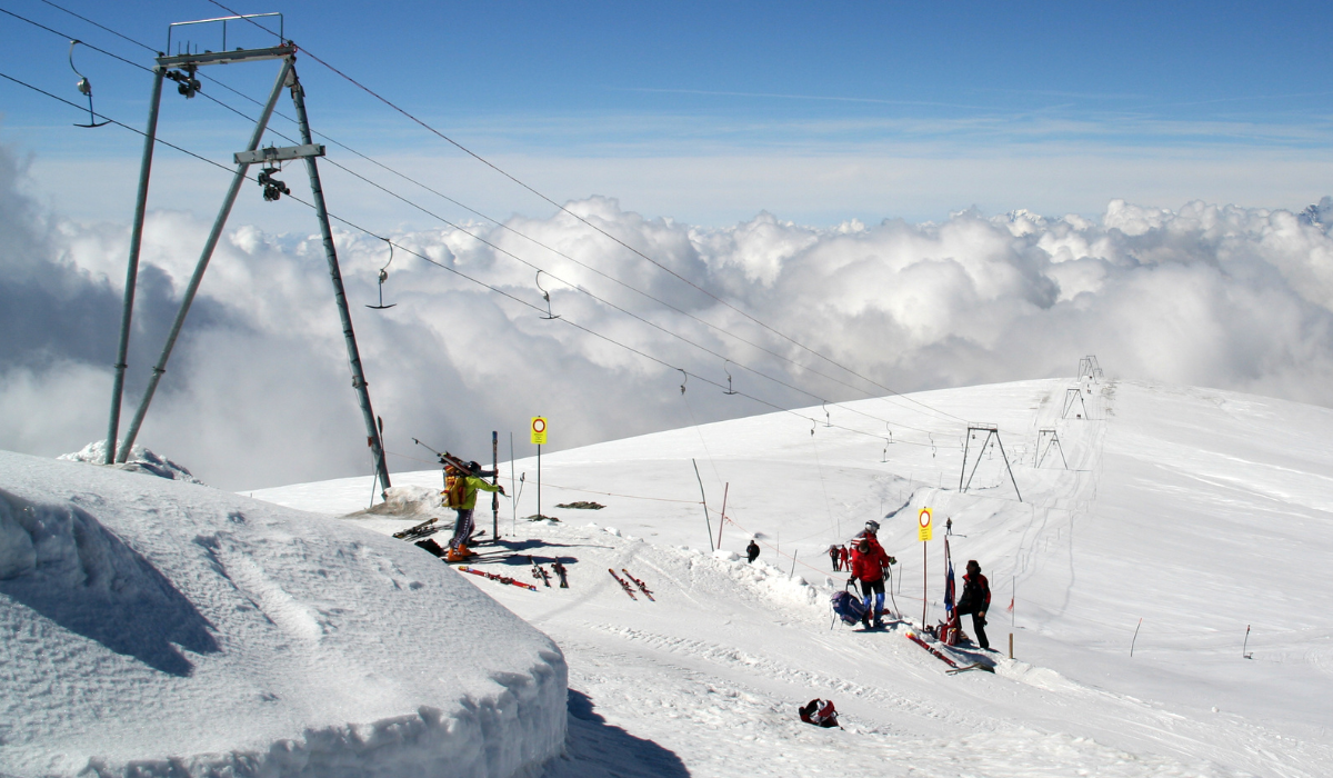 Button lift infrastructure above a completely white snow-covered view, with skiiers waiting at the top.