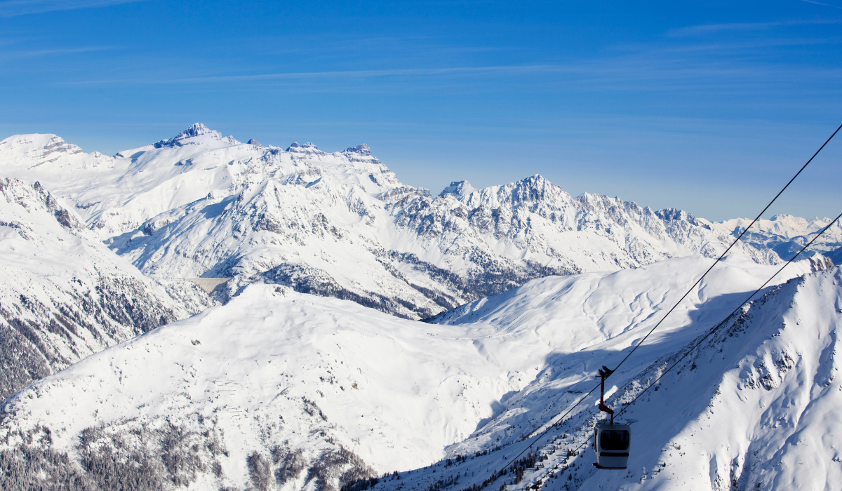 White, snow covered mountains, with cable gondola and wires to the right of the frame.